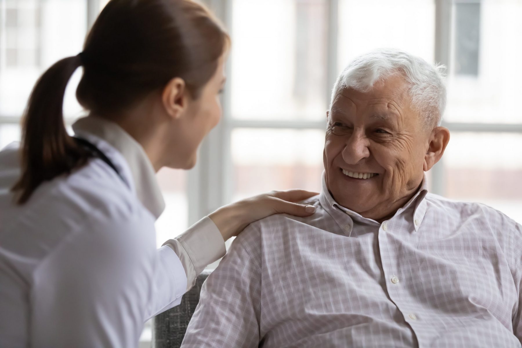 Liebevolle Pflegekraft bei der Betreuung eines älteren Patienten